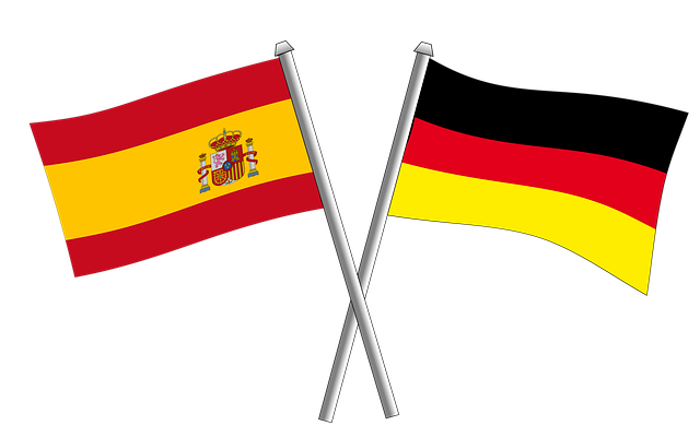 Gekreuzte Flaggen von Spanien und Deutschland auf silbernen Flaggenstangen