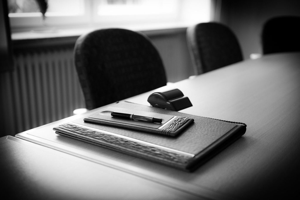 Schreibunterlage und Stift auf einem Besprechungstisch in einem juristischen Besprechungsraum